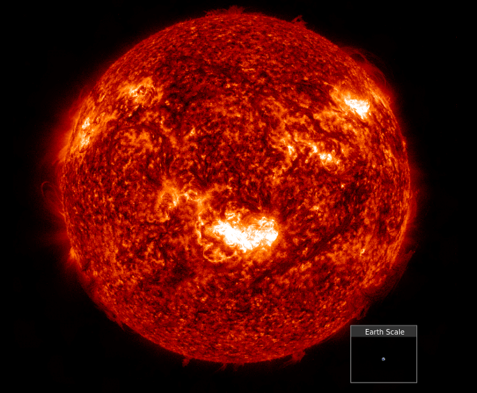A detailed, fiery image of the Sun showing bright solar flares and textured surface, with a small inset at the bottom right comparing the tiny size of Earth to the massive scale of the Sun.